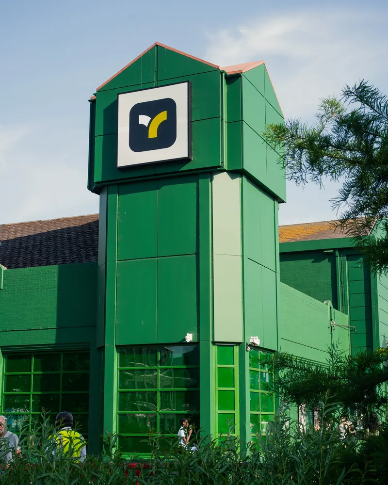 Teya HQ, the green building with its logo tower, seen from below.